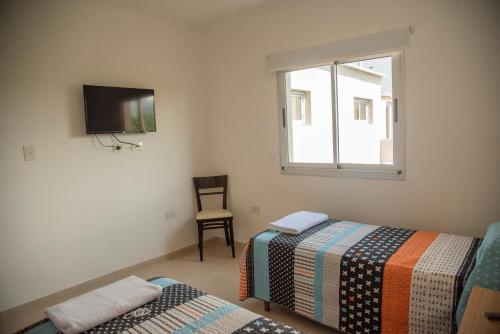 a room with two beds and a tv and a window at Morada Suites in Campana