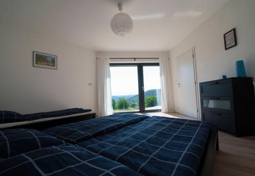 ein Schlafzimmer mit einem blauen Bett und einem großen Fenster in der Unterkunft Wellness bungalov - vodní nádrž Slapy - 40km od Prahy in Nečín