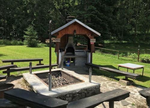 a small pizza oven in a park with benches at Ferienhaus Rauschenbachmühle in Arnsfeld