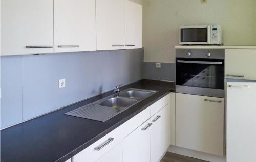 a kitchen with white cabinets and a sink and a microwave at Cozy Home In Vlagtwedde With Lake View in Vlagtwedde