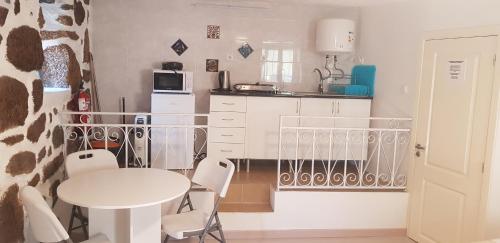 a small white kitchen with a table and chairs at Casa Bento Teixeira in Belmonte
