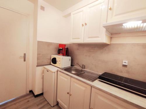 a kitchen with white cabinets and a sink and a microwave at Superbe studio pour 2 à 20m de la plage - 27 in Canet-en-Roussillon