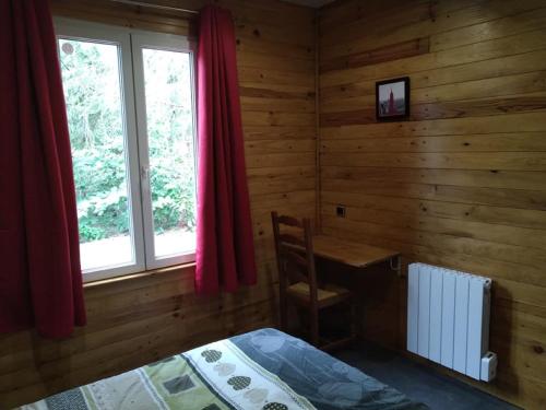 een slaapkamer met een bed, een bureau en een raam bij Chalet du Sanglier in Rancennes