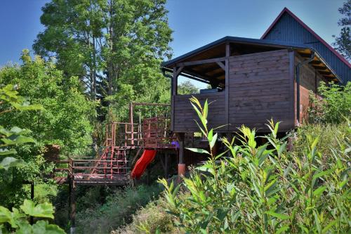 a tree house with a staircase in the woods at Chaloupka u lišáka in Sněžné