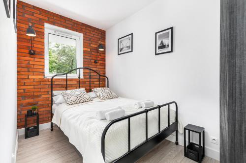 a bedroom with a bed and a brick wall at Apartamenty Solny Brzeg by Renters Prestige in Kołobrzeg