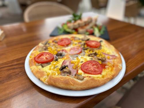 a pizza on a white plate on a table at Malom Club Panzió in Baja