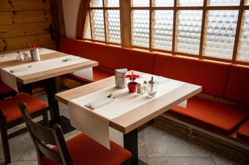 two tables in a restaurant with red seats at Alpenlodge Val Gronda in Obersaxen