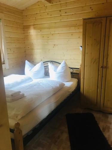 a bedroom with a bed with white sheets and pillows at Blockhaus Harzblick4C in Braunlage