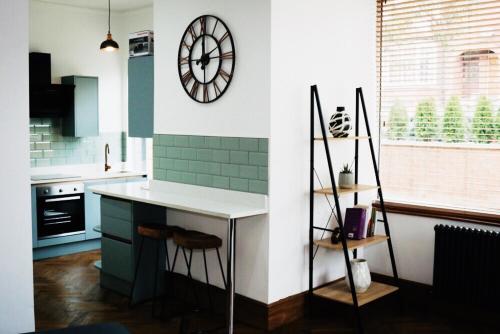 a kitchen with a clock on the wall and a counter at Newly refurbished apartment in Chapel Allerton, Leeds in Moortown
