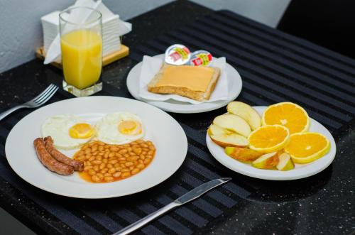 two plates of breakfast food on a table with oranges and eggs at Residencial Horizonte 2 in Maputo