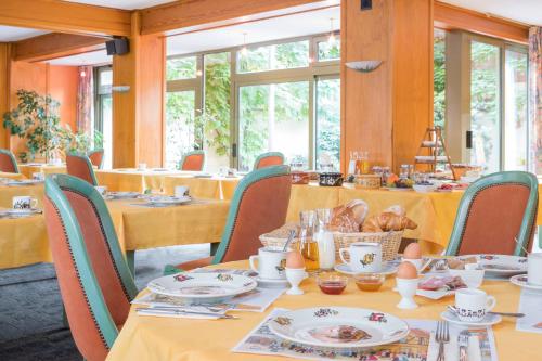 ein Esszimmer mit Tischen und Stühlen mit Essen drauf in der Unterkunft Hôtel A la Vignette - COLMAR-NORD in Saint-Hippolyte