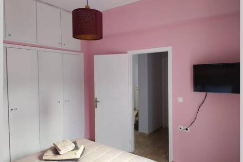 a bedroom with a pink wall with a phone on a bed at IRIS by Amanakis Family in Hersonissos