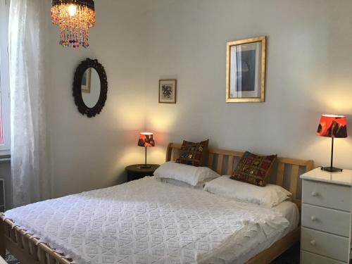 a bedroom with a bed with two lamps and a mirror at Maison de la Fontaine in Embres-et-Castelmaure