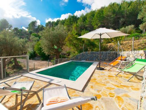 a swimming pool with an umbrella and chairs and a table and an umbrella at Villa Mancor Pool & Mountain Views in Mancor del Valle