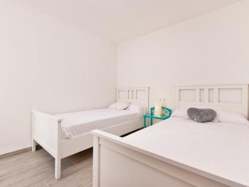 two beds in a bedroom with white walls and wooden floors at Apartment Mar del Plata in Alcudia beach in Alcudia