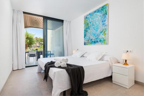 Habitación blanca con cama y balcón. en Mirador Blue F - Cala Sant Vicenç, en Cala de Sant Vicent