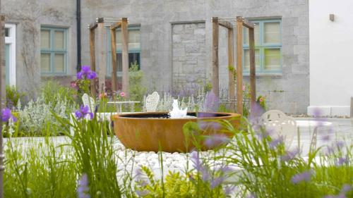 a fountain in the middle of a garden with flowers at Dromoland Castle in Newmarket on Fergus