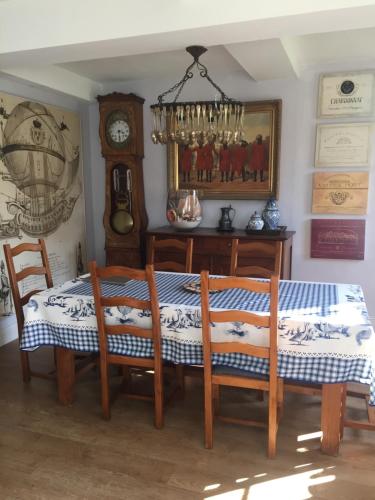 ein Esszimmer mit einem Tisch, Stühlen und einer Uhr in der Unterkunft La carpe Diem in Les Damps
