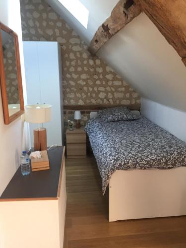 ein Schlafzimmer mit einem Bett und einem Tisch mit einer Lampe in der Unterkunft La carpe Diem in Les Damps