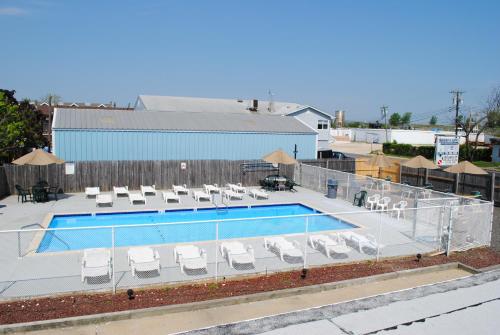 a swimming pool with lounge chairs and a swimming poolvisor at Shore Point Motel in Point Pleasant Beach