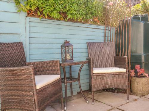 two chairs and a table with a lamp on a patio at 3 Lowerbourne Terrace in Minehead
