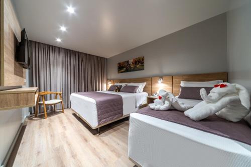 a hotel room with two beds with stuffed animals on them at Hotel Laghetto Fratello in Gramado