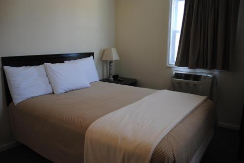 1 dormitorio con 1 cama con sábanas blancas y ventana en Shore Point Motel, en Point Pleasant Beach