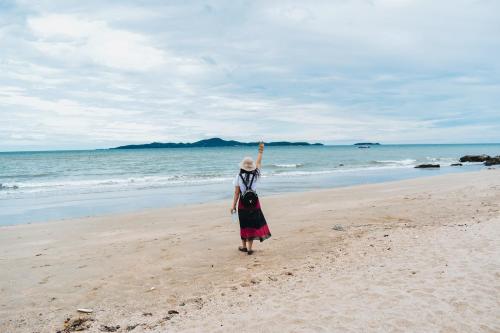 a woman standing on a beach with her arm in the air at The Pool House Pattaya No.8 in Pattaya South