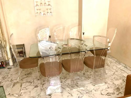 a glass dining table with four chairs on a marble floor at Chill Out Apartment, 2 mins from beach in Nice