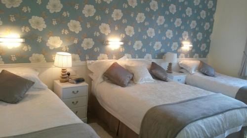 2 camas en un dormitorio con papel pintado con motivos florales en Shannonside House N37HF67 en Athlone