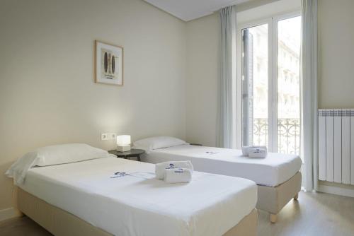 Duas camas num quarto com uma janela em Xingola - Basque Stay em San Sebastián