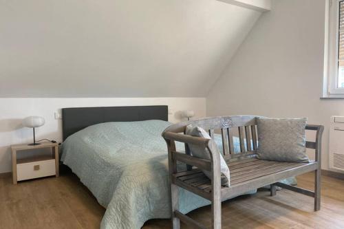 um quarto com uma cama e uma cadeira de madeira em Gite "Le Platane" 45 m2 - climatisé em Monswiller