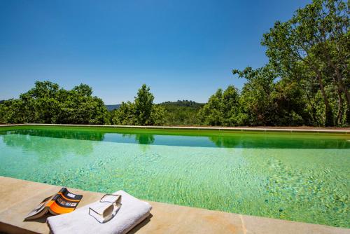 a swimming pool with a pair of towels on a table at Bastide Saint-Estève in Brue-Auriac