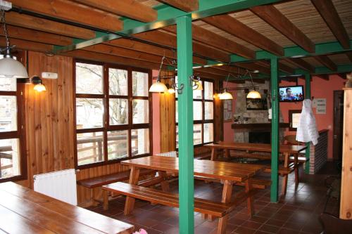 um restaurante com mesas de madeira numa sala com janelas em Albergue Peña Castil em Sotres