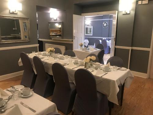 a dining room with tables and chairs with white table cloth at The Hotel Commodore in Llandrindod Wells