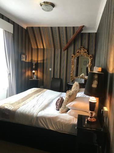 a bedroom with a large bed and a mirror at The Hotel Commodore in Llandrindod Wells