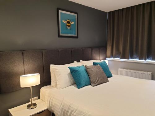 a bedroom with a large bed with blue pillows at The Spires Serviced Apartments Cardiff in Cardiff