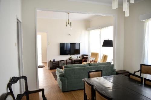 a living room with a green couch and a tv at A Casa do Outeiro in Ribeira Grande