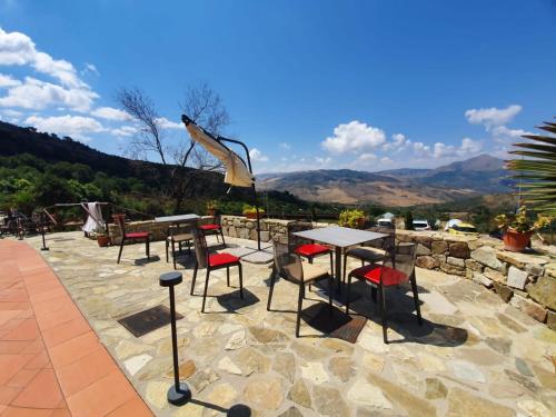 una mesa y sillas en un patio con montañas al fondo en Resort San Nicola - Restaurant and Wellness Fitness, en Polizzi Generosa
