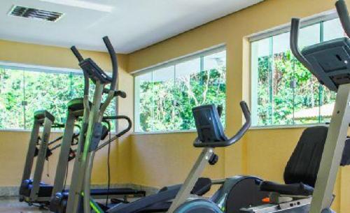 a gym with three elliptical machines in a room with windows at Apartamento Lacqua Di Roma III in Caldas Novas