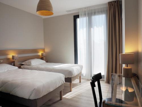 una camera d'albergo con due letti e un tavolo in vetro di Le Roc'h Ar Mor a Lampaul