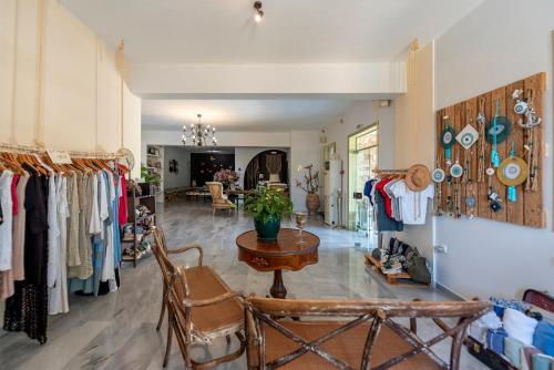 a room with a table and chairs and racks of clothes at Parosland Hotel in Aliki
