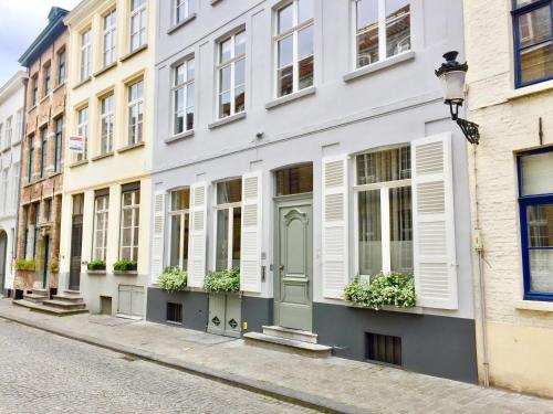 a white building with white shutters on a street at B&B Setola in Bruges