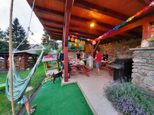a patio with a table and a hammock and people at Penzion Garden in Cerny Dul