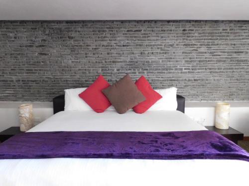 1 dormitorio con 1 cama grande con almohadas rojas y moradas en Hotel & Spa Luna Canela Boutique, en Atlixco