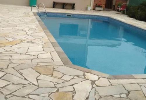 una piscina con pavimento in pietra e acqua blu di Apartamento Condomínio Boiçucanga Flat N 39 - Apto 10 a Boicucanga