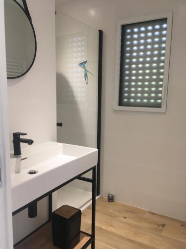 a bathroom with a white sink and a window at kercady 1 in Audierne