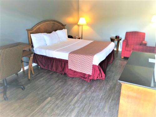 a hotel room with a bed and a red chair at Countryside Inn Richmondville in Richmondville