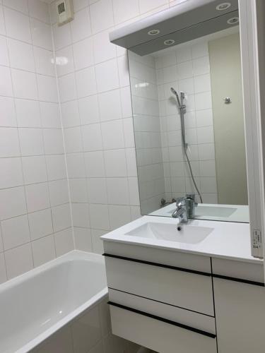 a white bathroom with a sink and a bath tub at F2 rénové lumineux dans résidence avec balcon et parking in Talange