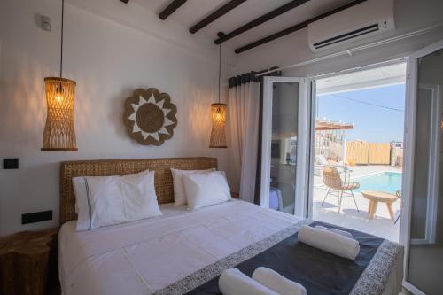 a bedroom with a large white bed with a balcony at SeaCode Villas in Platis Gialos